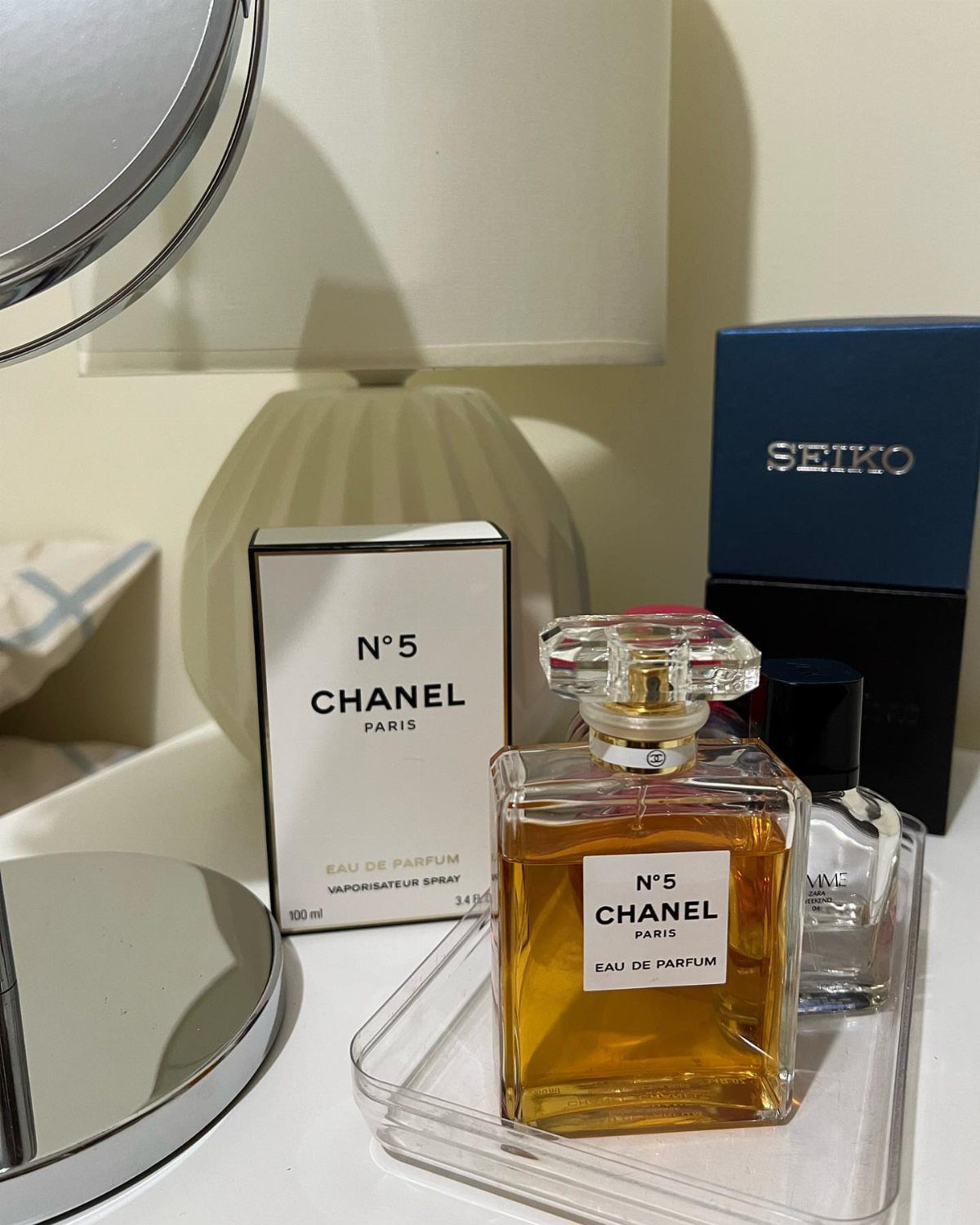 Chanel No. 5 perfume bottle and box on a clear acrylic tray.