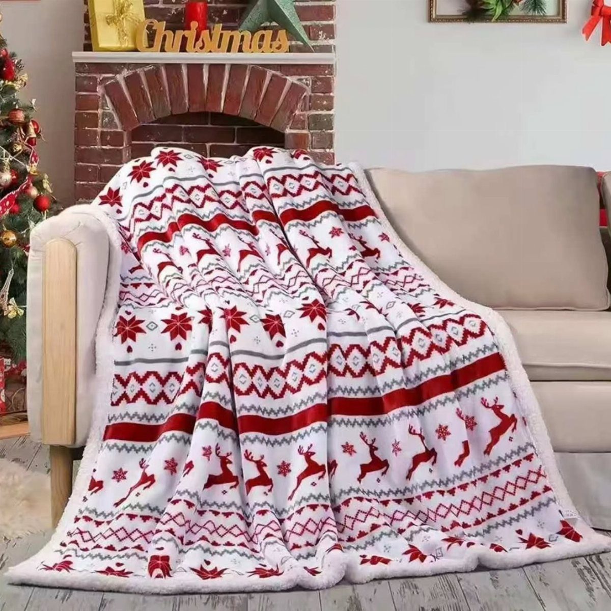 Red and white reindeer patterned plush blanket draped over a beige living room sofa