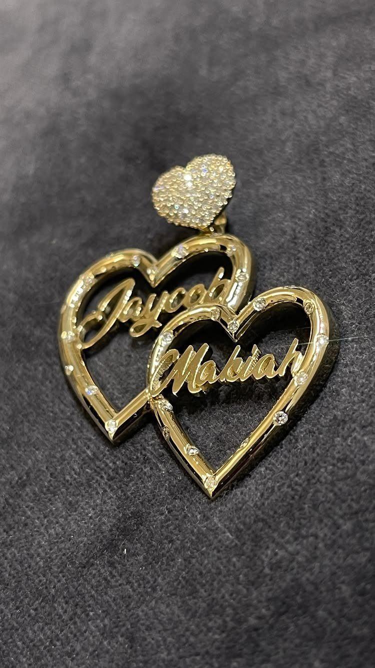 Gold interlocking heart necklace pendant with engraved names Jaycola and Makiah on dark fabric