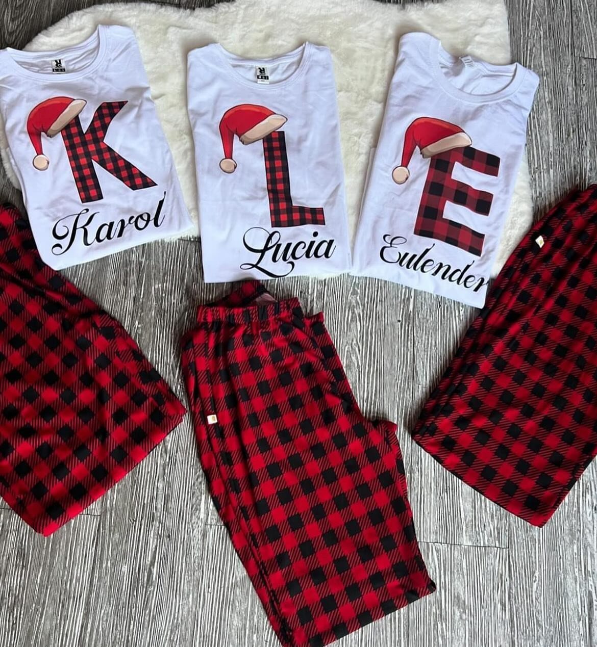 Three sets of personalized Christmas pajamas with red plaid pants and white shirts.