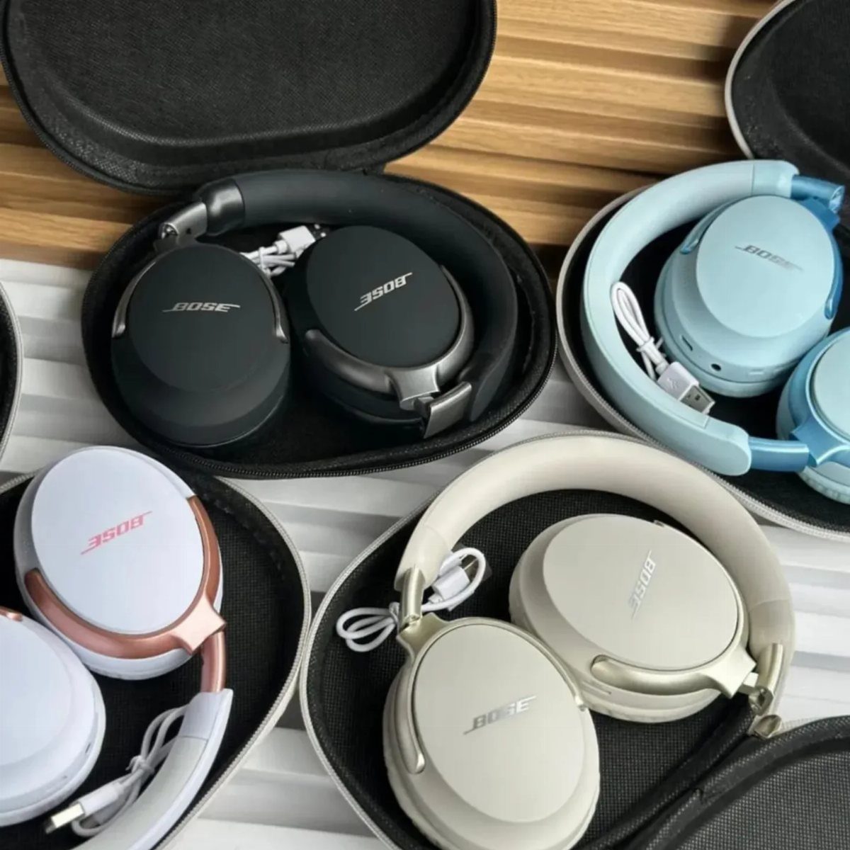 Bose noise-cancelling headphones in various colors resting in black protective carrying cases.
