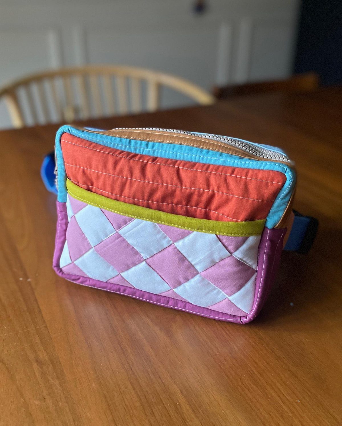 Colorful quilted belt bag with red, green, and pink diamond patterns on wooden table