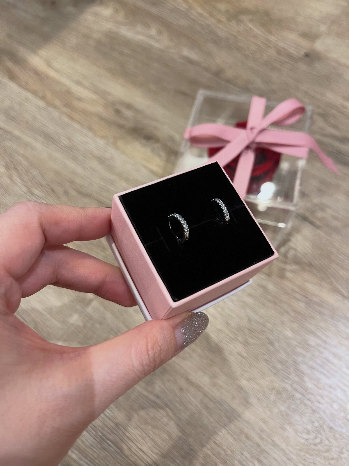 Silver crystal hoop earrings in a pink box held by a hand