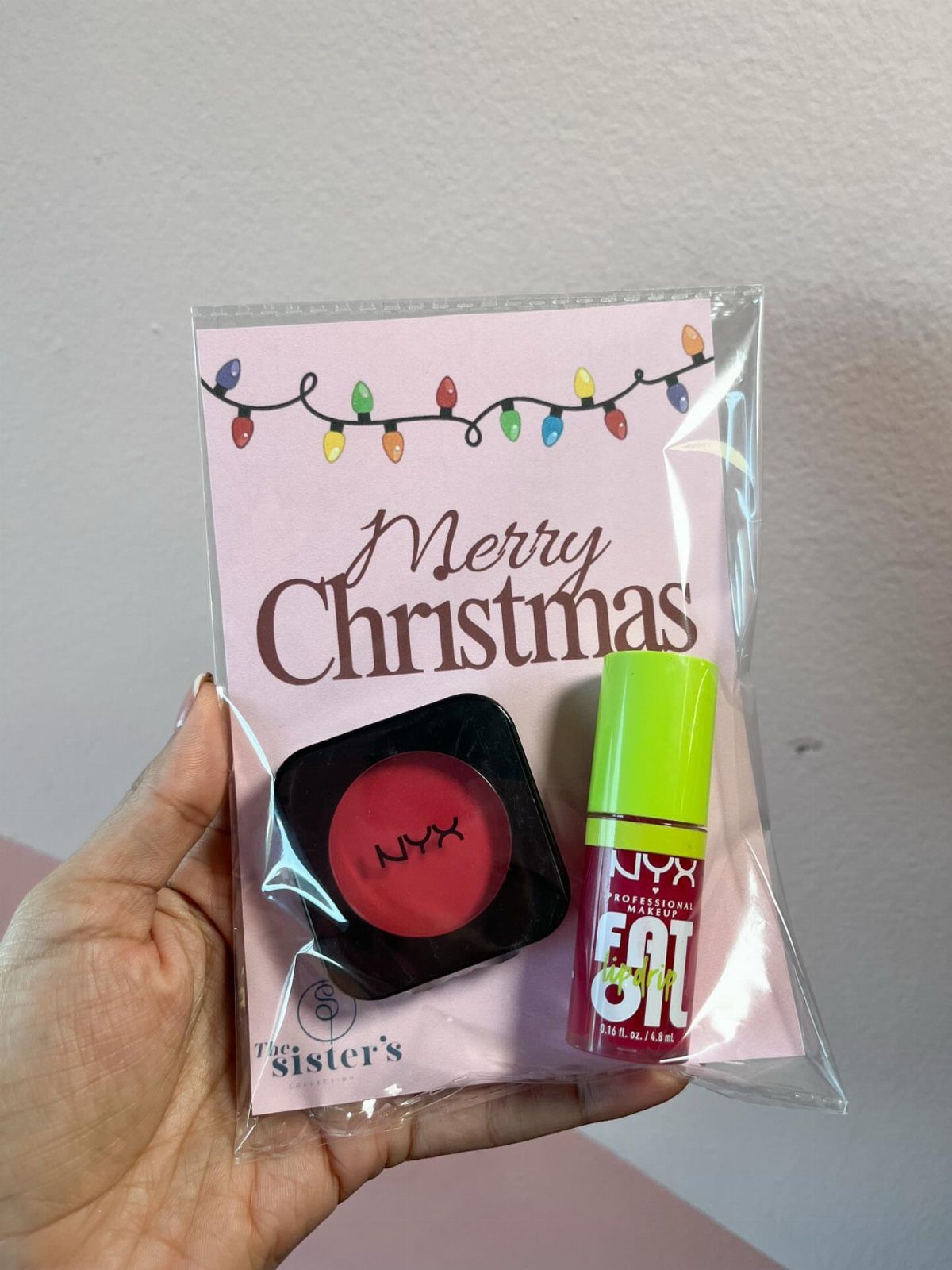 Hand holding a clear gift bag with makeup and a Merry Christmas card.