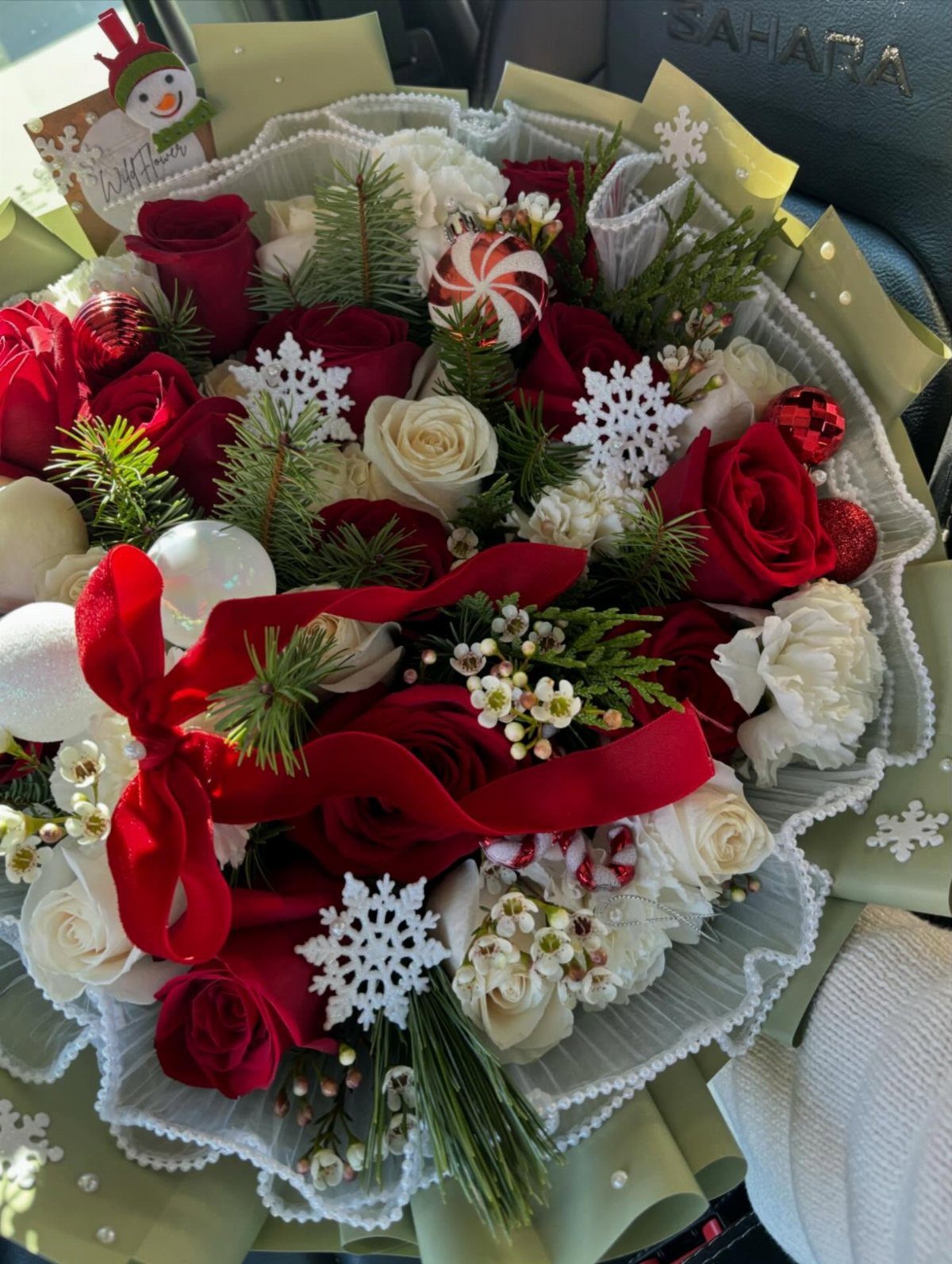 Festive bouquet of red and white roses with snowflakes and a red ribbon.