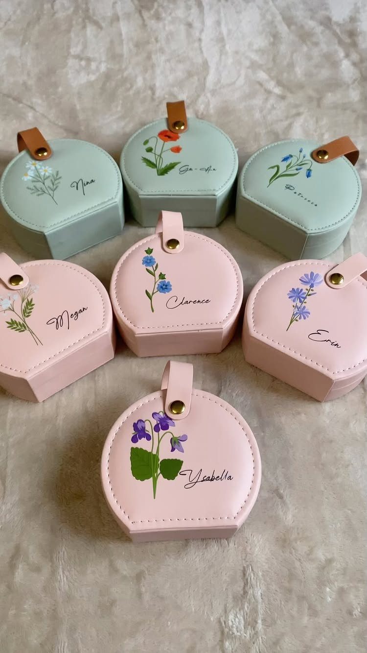 Small hexagonal jewelry boxes in pink and mint with floral paintings and names.