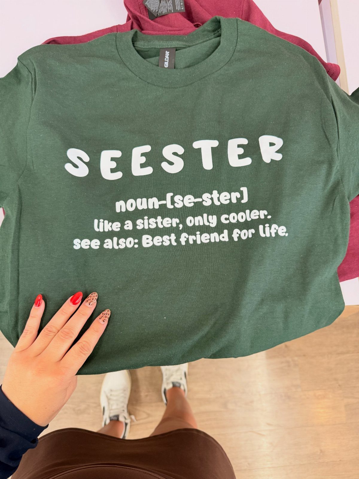 Green t-shirt with a funny dictionary definition of seester held by a person