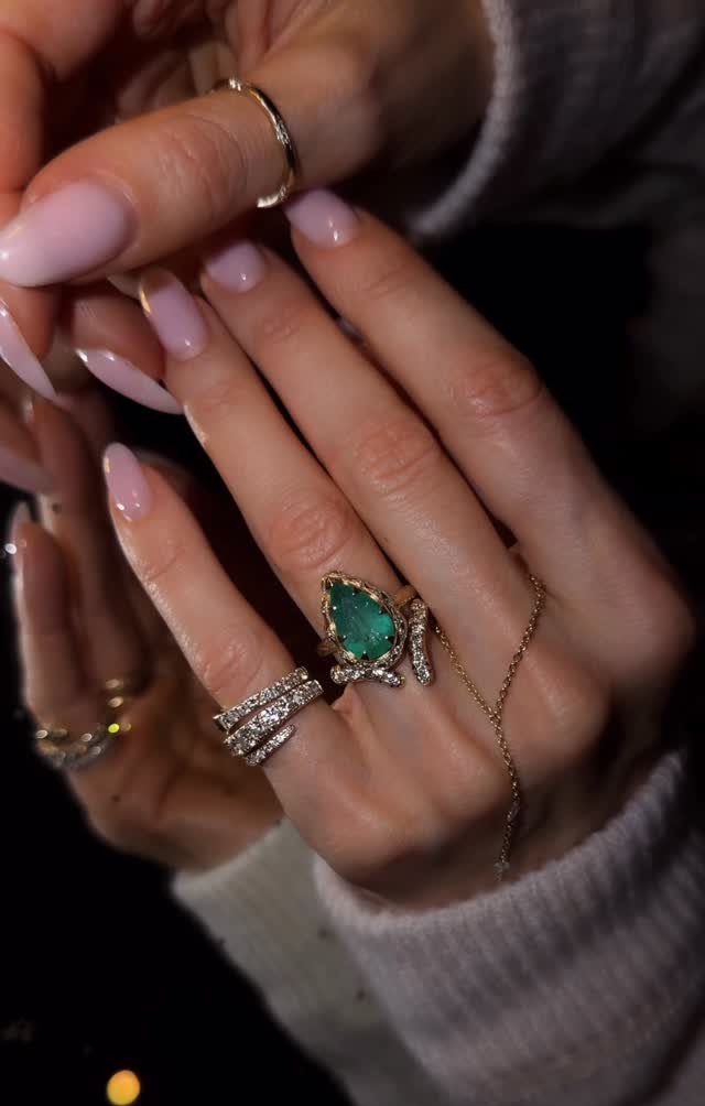 Woman's hands wearing gold diamond rings and a green emerald ring