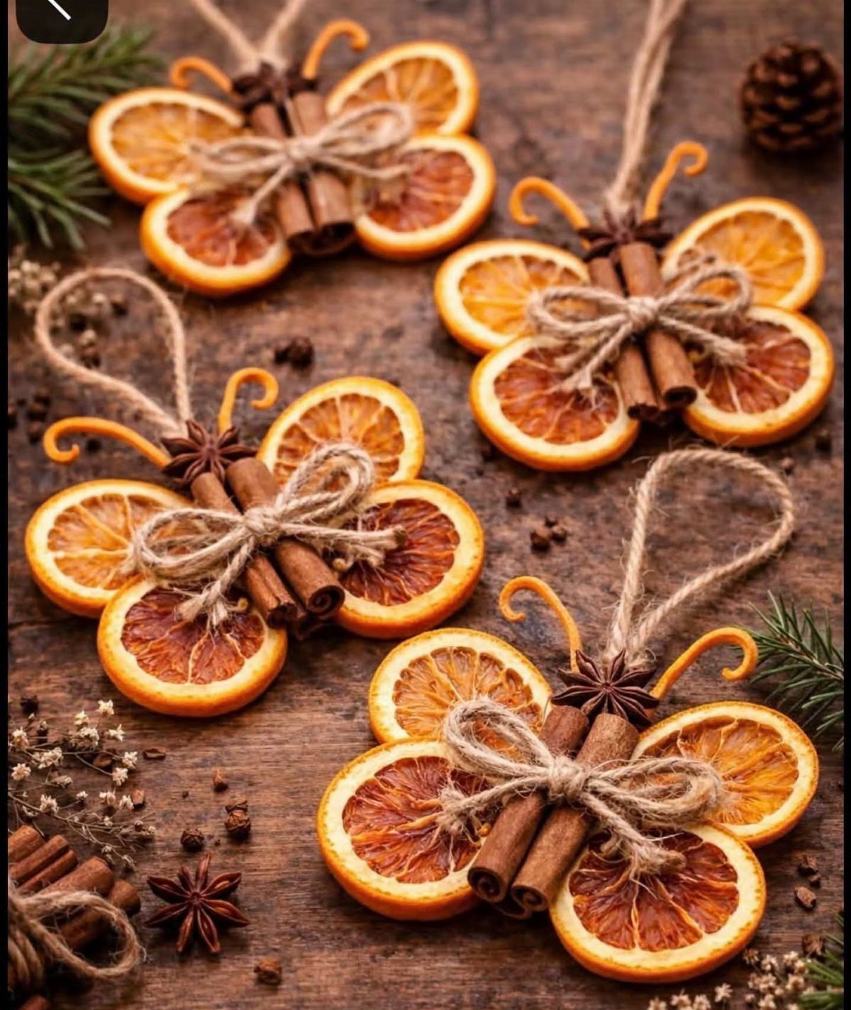 Dried orange slice ornaments with cinnamon sticks and twine on a wooden table.