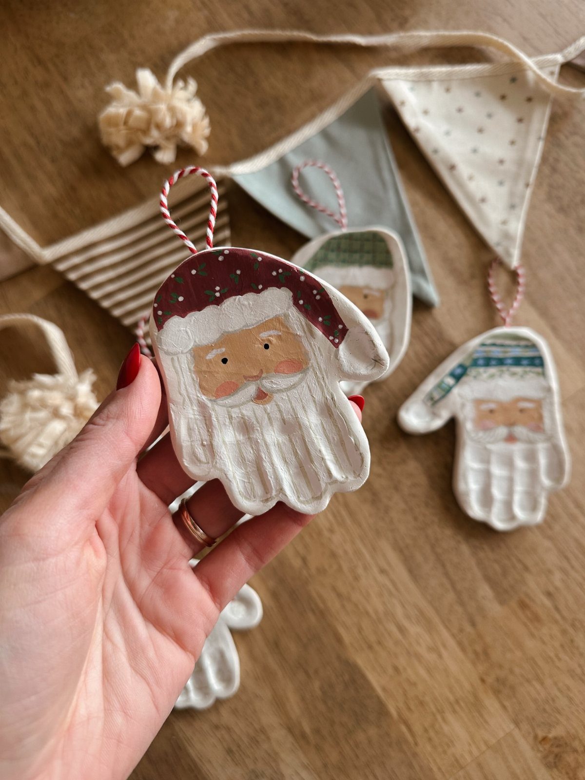 Handprint Santa ornament made from ceramic, painted with a red hat and beard.