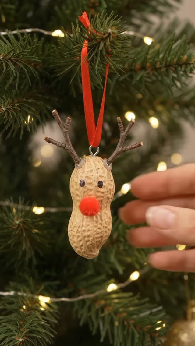 Peanut shell reindeer ornament with twig antlers hanging on a lit Christmas tree
