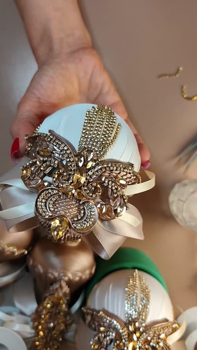 White Christmas ornament decorated with a gold rhinestone brooch and satin ribbon.
