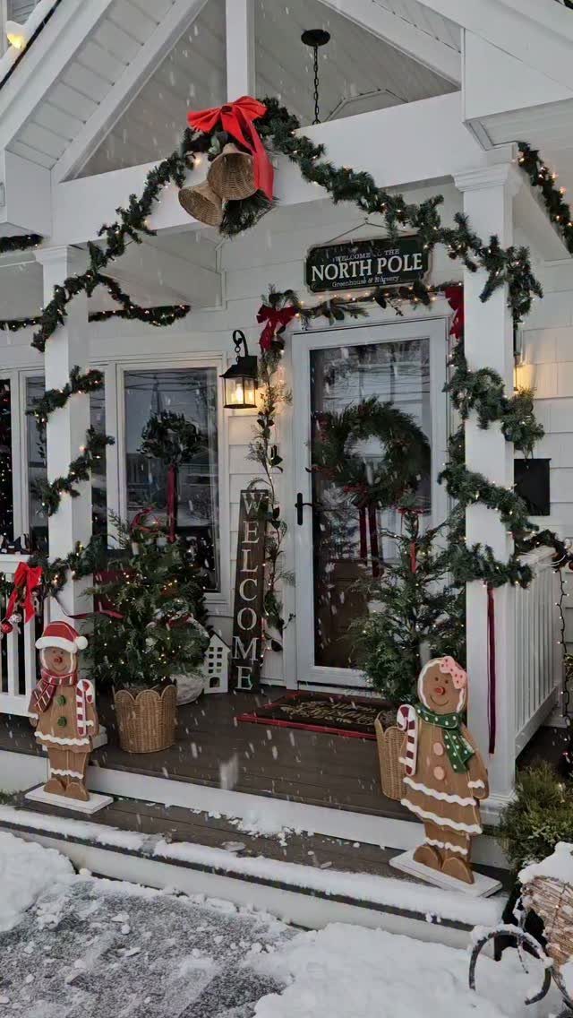 Christmas porch with green garlands, gingerbread man figures, and small potted evergreen trees.