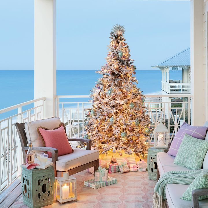 Decorated Christmas tree on a coastal porch with pastel furniture overlooking the ocean.