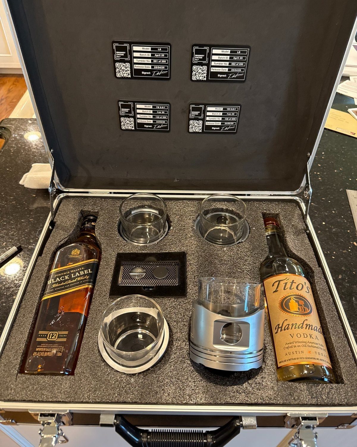 Alcohol gift set in a silver briefcase with scotch, vodka, and glasses.