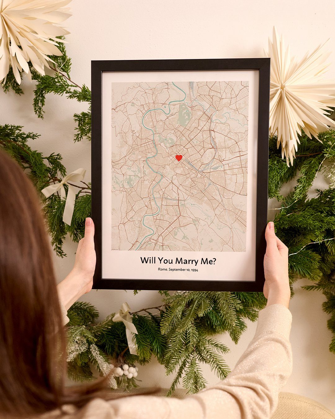 Framed custom map print with a red heart and proposal text held by person