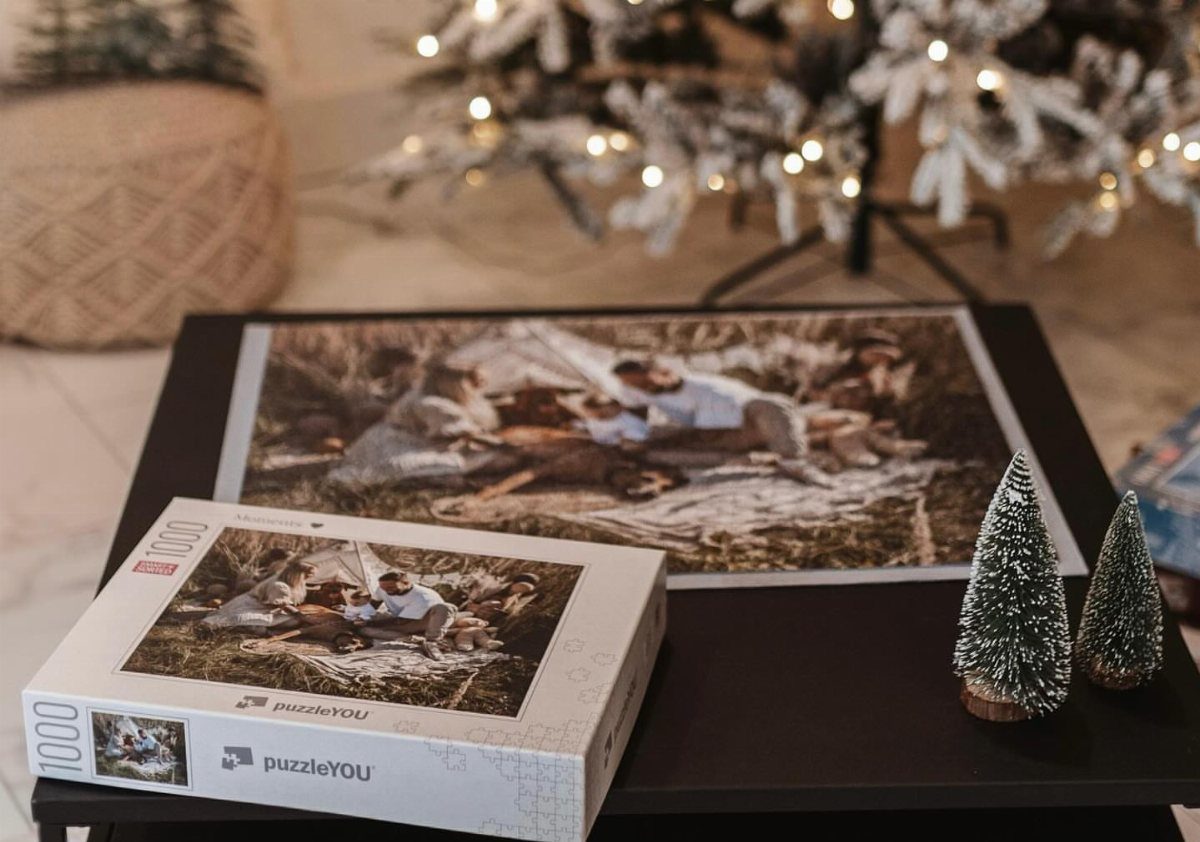Custom photo puzzle and box on a table with Christmas decorations in background