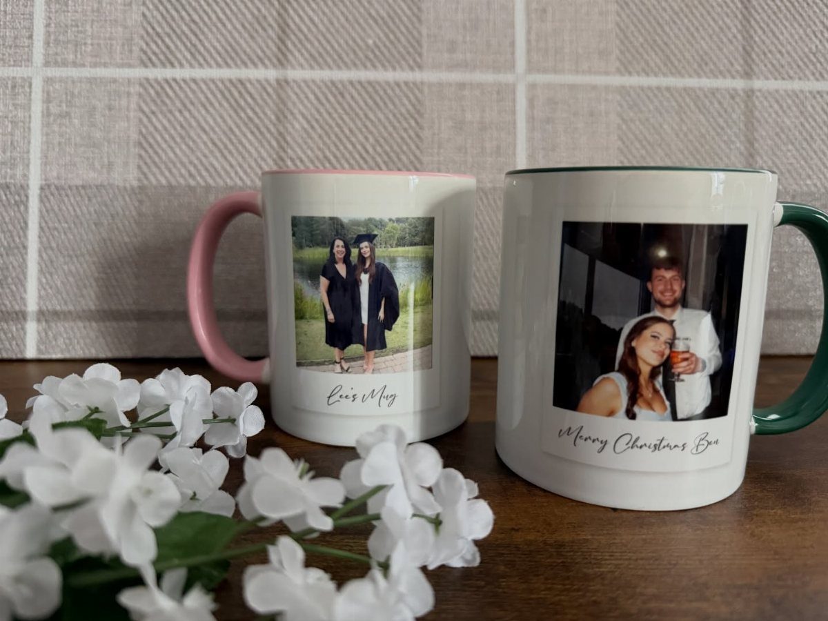Two personalized photo mugs with pink and green handles on a wooden table.