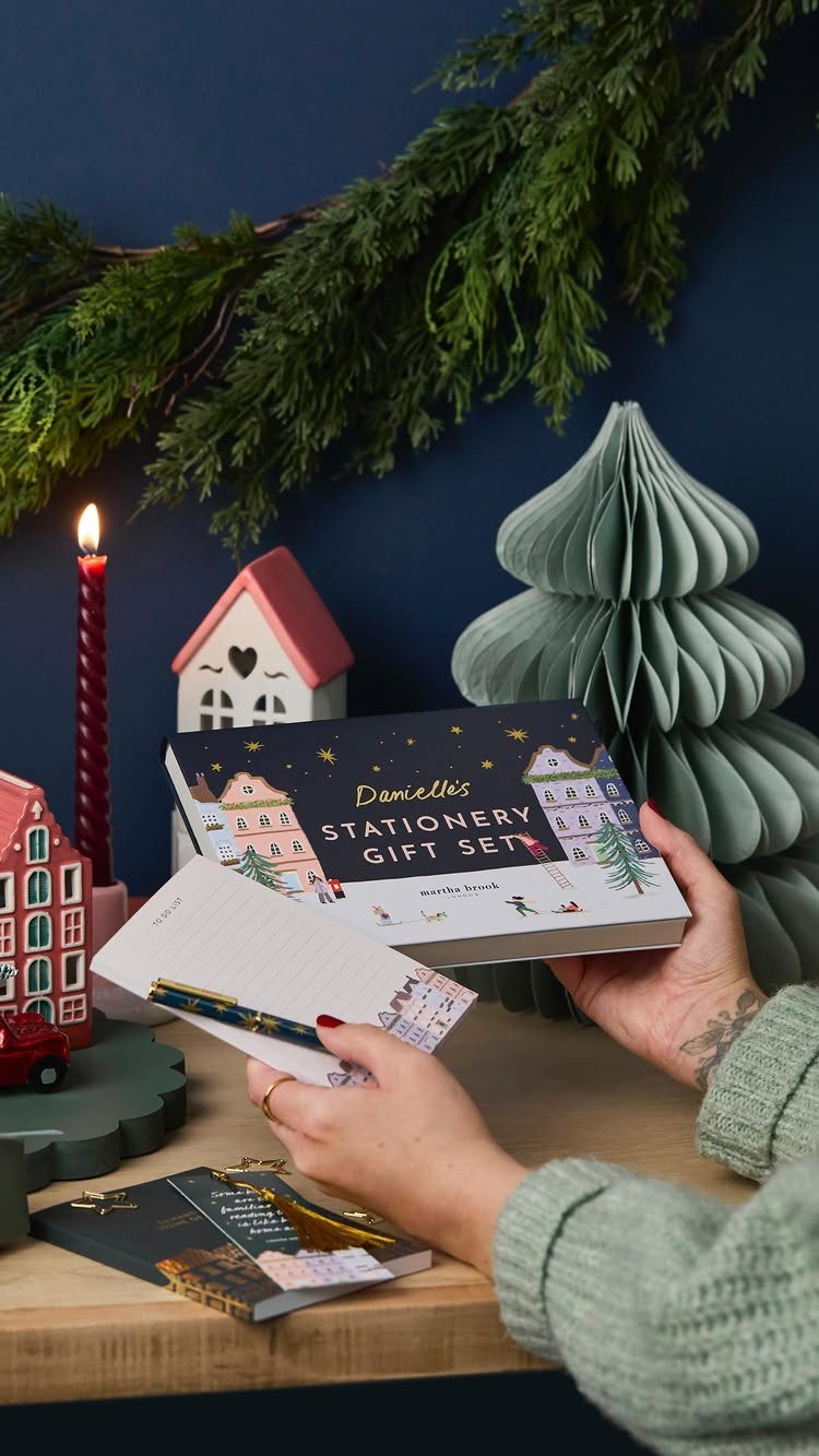 Stationery gift set with notepad and pen held by hands in festive setting