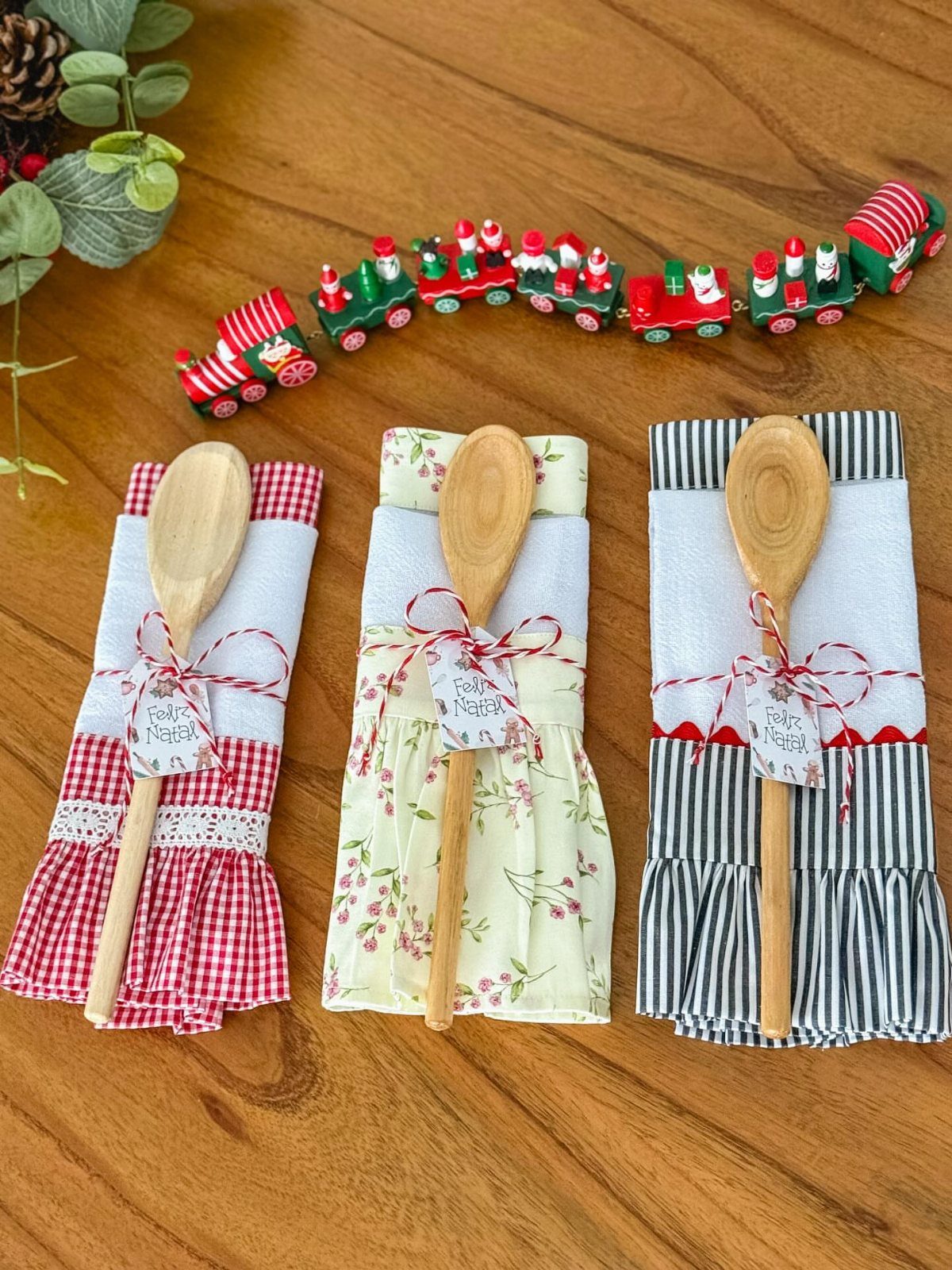 Three wrapped wooden spoons with fabric napkins and tags on a wooden table