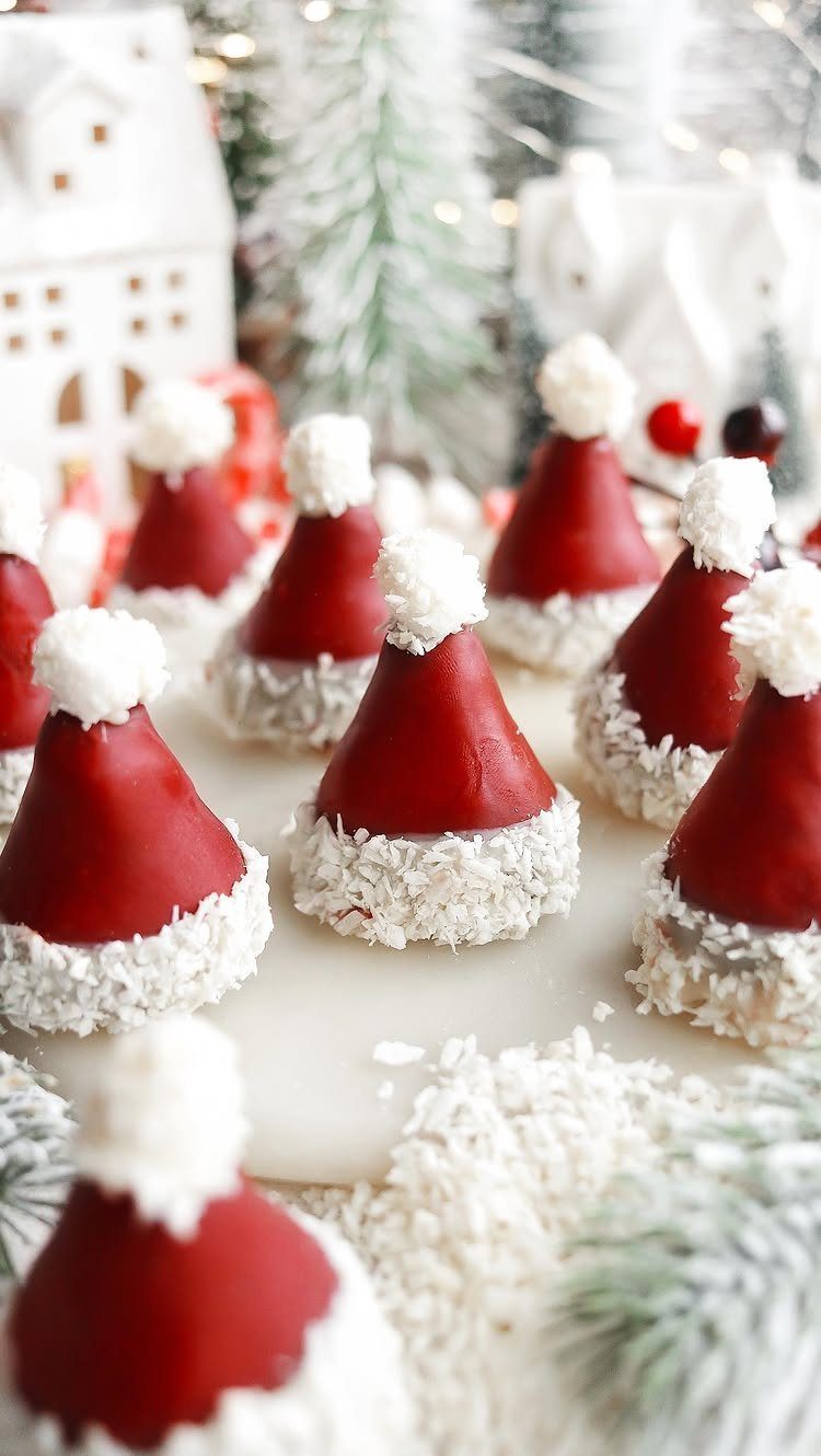 Santa hat shaped treats with red coating and coconut trim on white surface