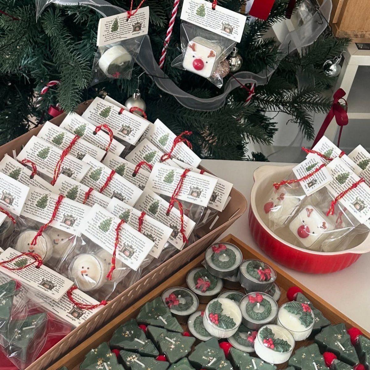 Handmade Christmas candles shaped like snowmen and trees wrapped for holiday gifting.