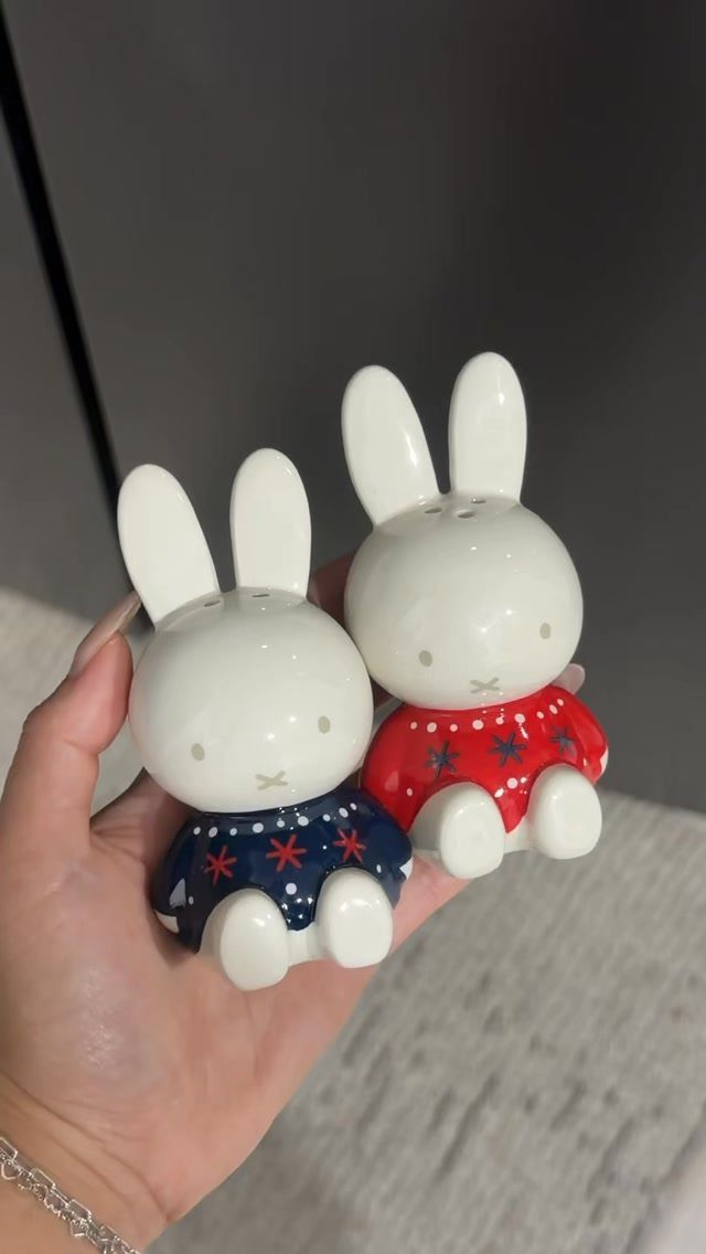 Two ceramic rabbit salt and pepper shakers wearing red and blue star sweaters.