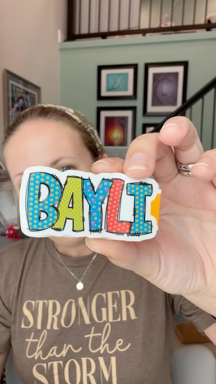 Colorful comic-style name tag held up in front of a woman indoors.