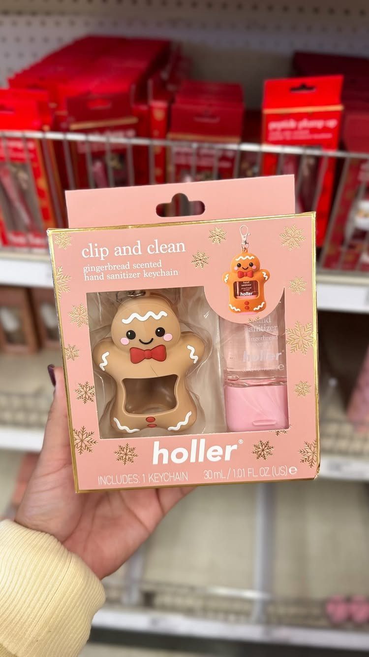 Gingerbread man hand sanitizer keychain in pink packaging held in a hand.
