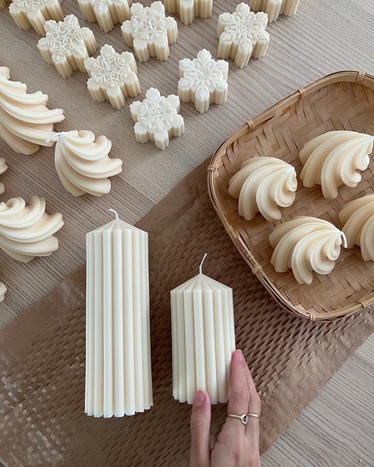 White wax candles in snowflake and pillar shapes on a wooden table.