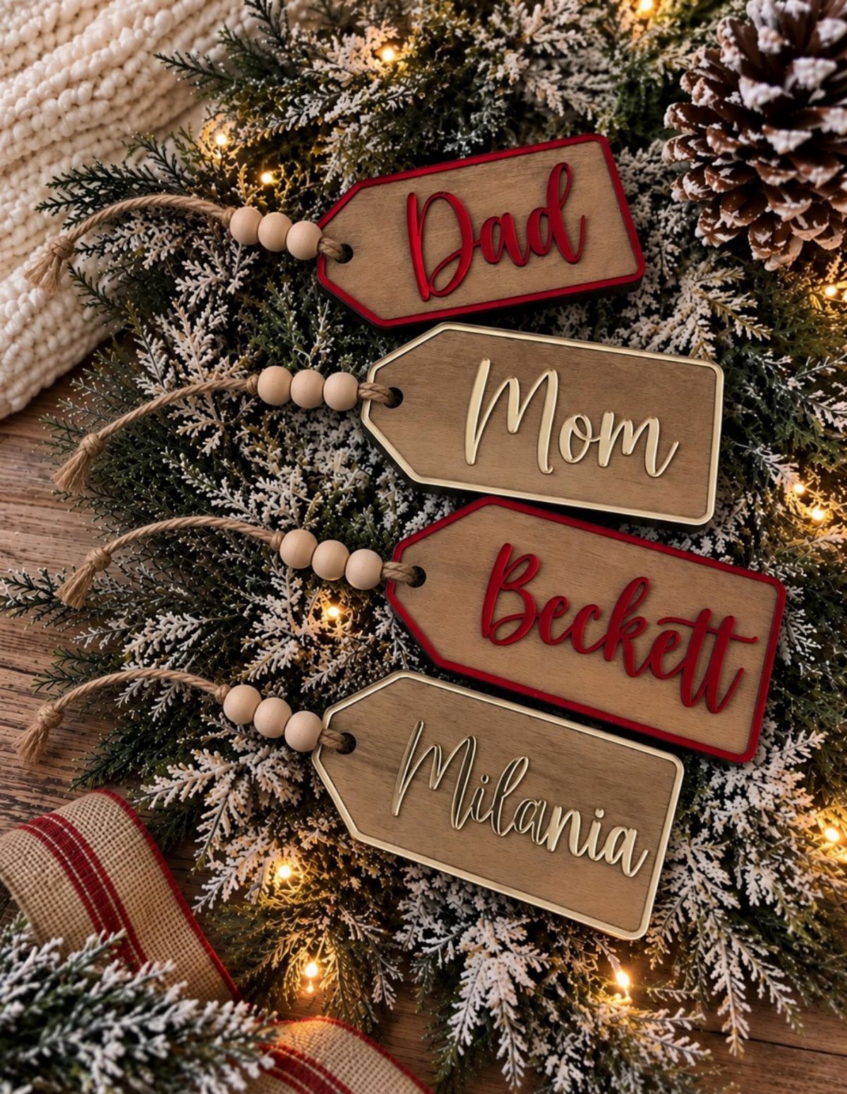 Wooden personalized Christmas ornaments with names resting on a lit evergreen branch.