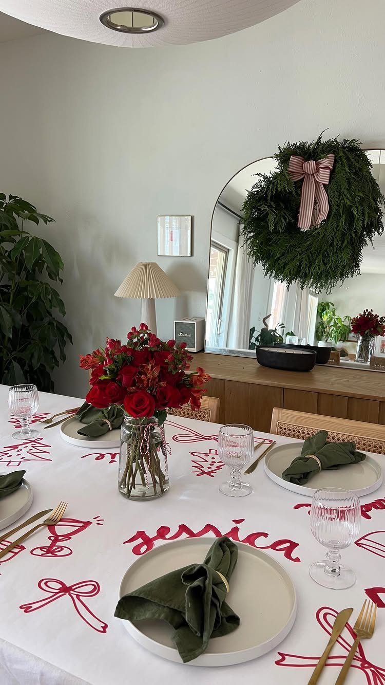 White tablecloth with red embroidery set with green napkins and red roses