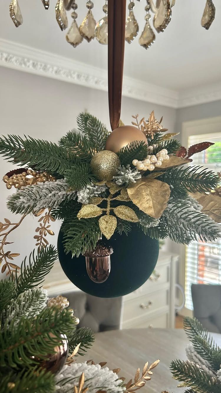 Christmas arrangement with gold ornaments and greenery hanging from a crystal chandelier