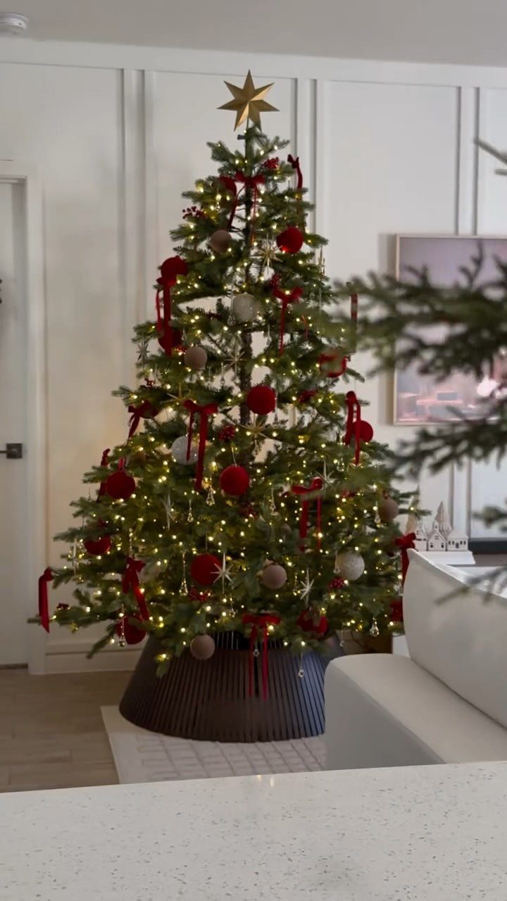 Christmas tree decorated with red velvet bows, red ornaments, and a gold star topper.