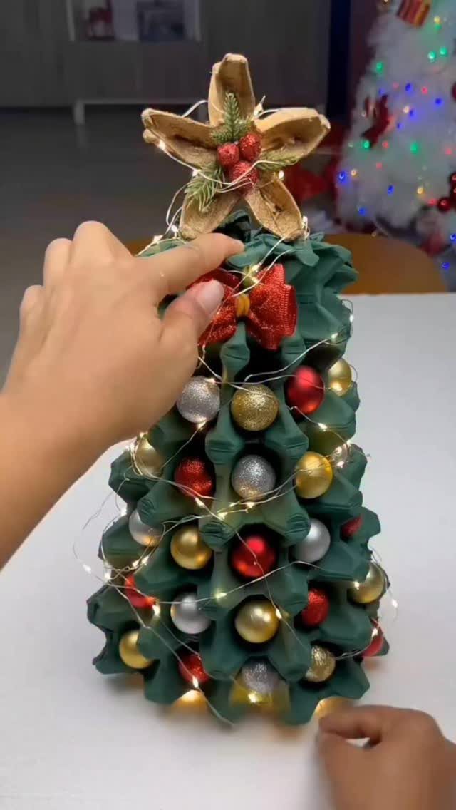 Egg carton Christmas tree painted green and decorated with colorful baubles and lights.