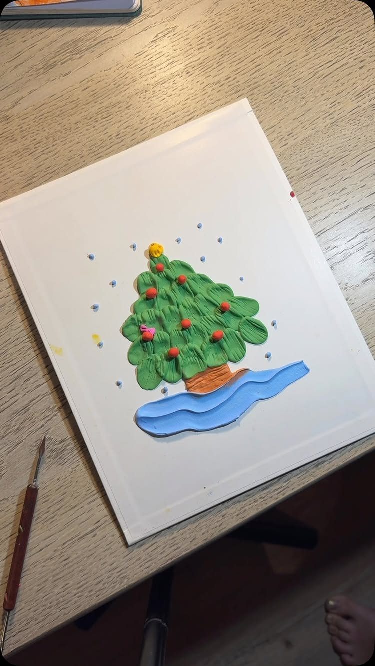 Green playdough Christmas tree with colorful pony bead ornaments on a white canvas.