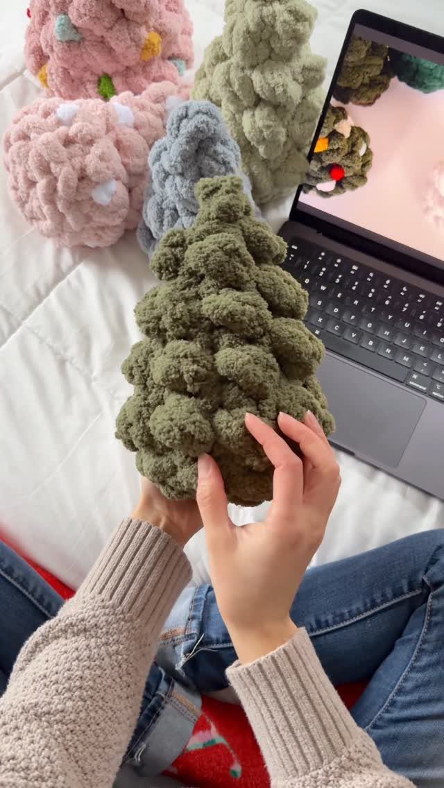 Green crochet yarn Christmas tree held by a person on a white bed
