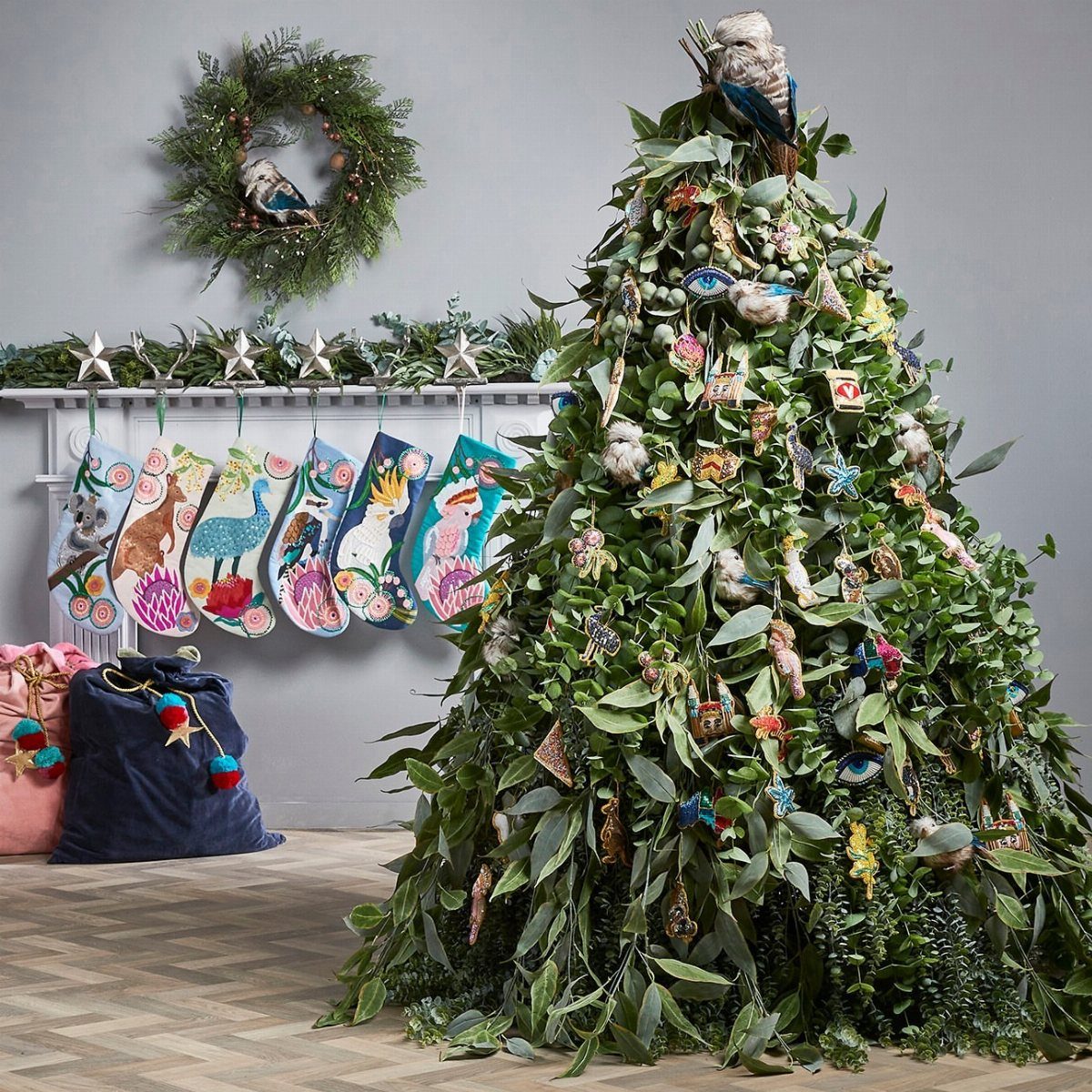 Green Christmas tree with bird ornaments and a bird topper in a decorated room