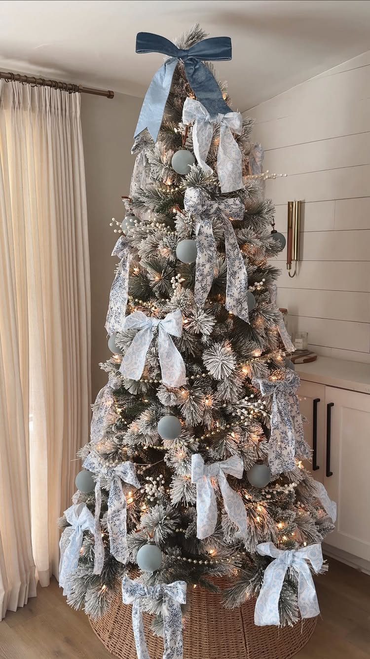 Flocked Christmas tree decorated with light blue ribbons, bows, and blue ornaments.