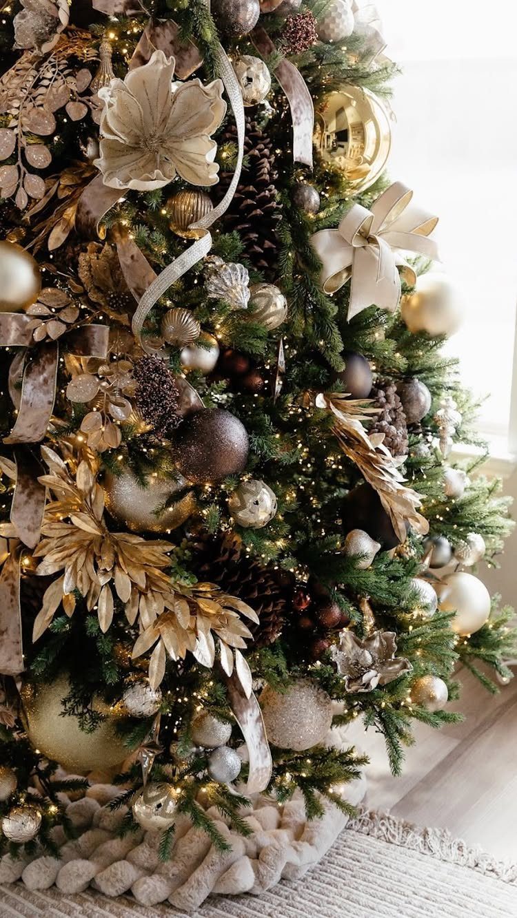 Decorated Christmas tree with gold ornaments, cream flowers, and warm white fairy lights.
