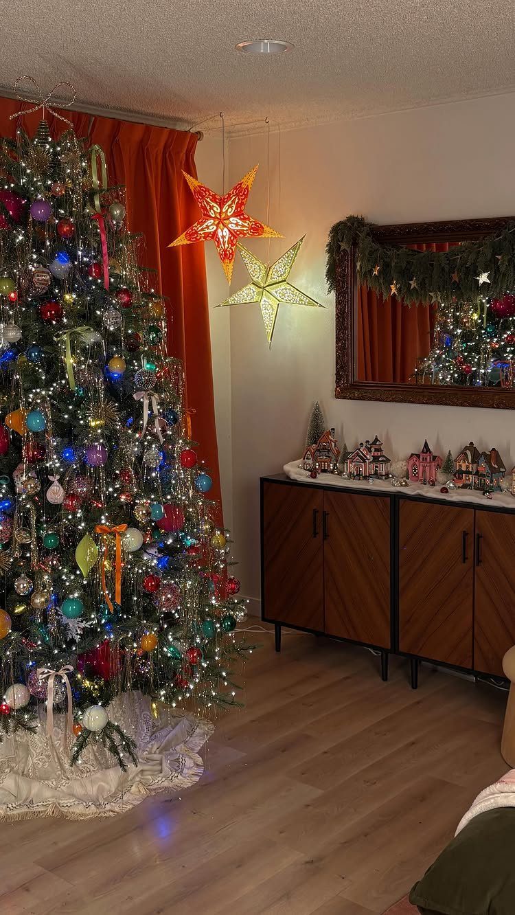 Densely decorated Christmas tree with multicolored ornaments and glowing star lanterns in a room.