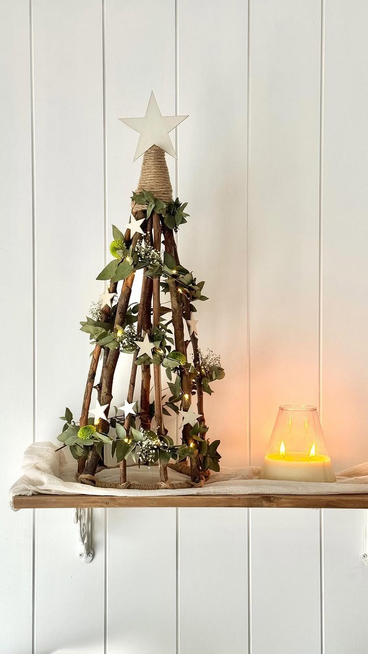 Wooden branch Christmas tree with green leaves and white star topper on shelf