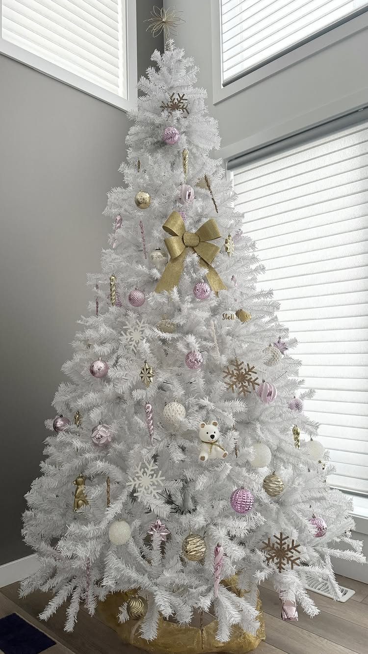 White Christmas tree decorated with gold bows, pink and gold ornaments, and snowflakes.