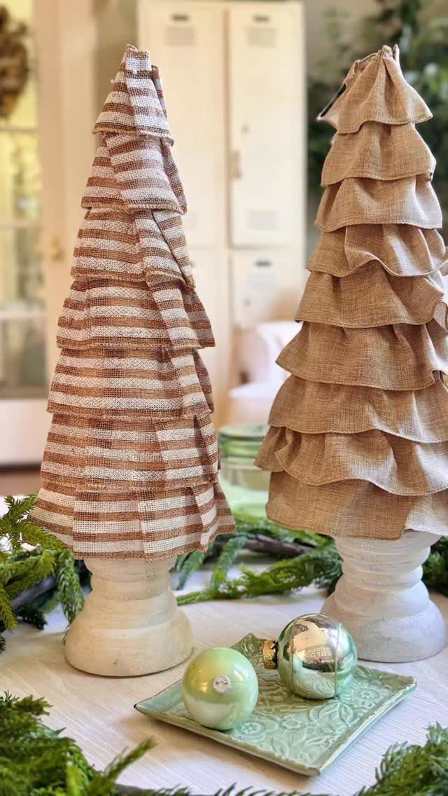 Two small decorative Christmas trees crafted from striped and solid tan burlap fabric.