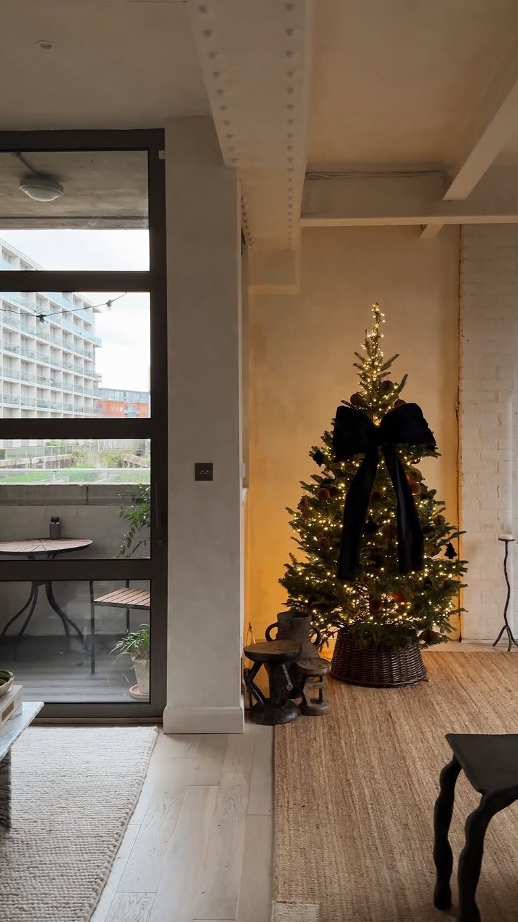 Christmas tree with warm lights and a large black velvet ribbon bow.