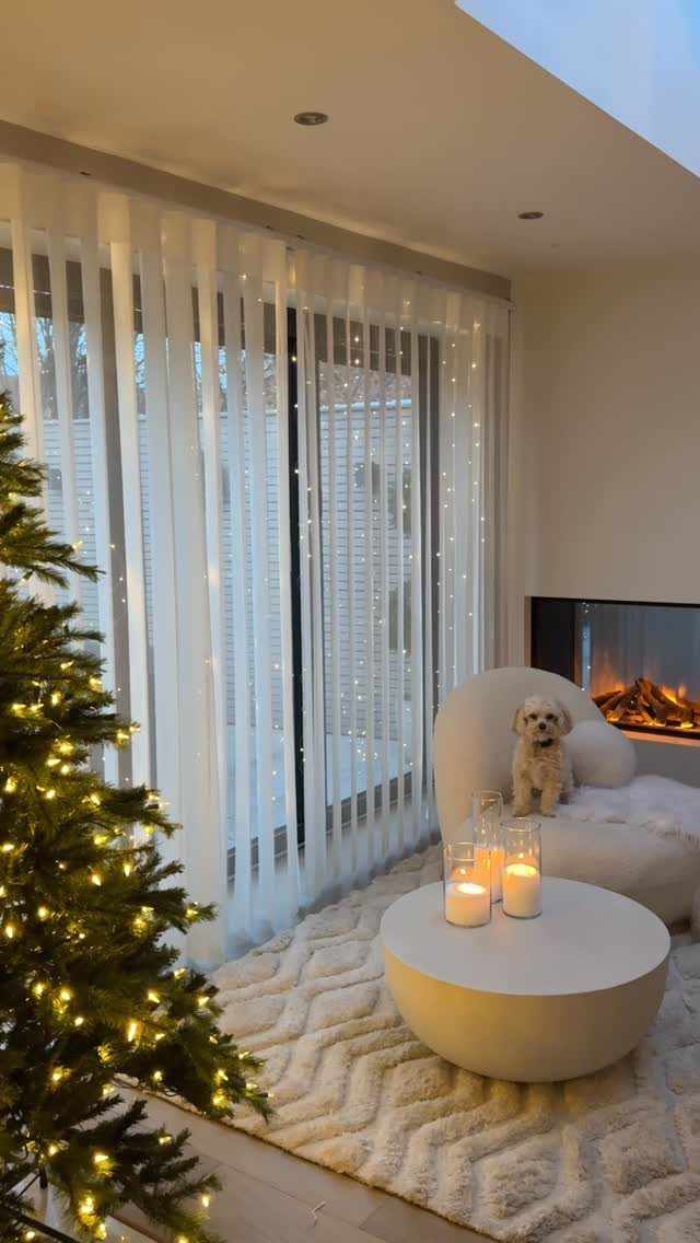 Curtain lights hanging behind sheer white window curtains in a cozy living room.