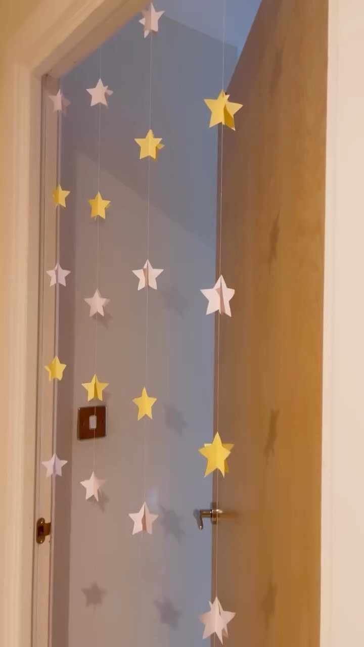 Yellow and white paper stars hanging on strings in a window frame.