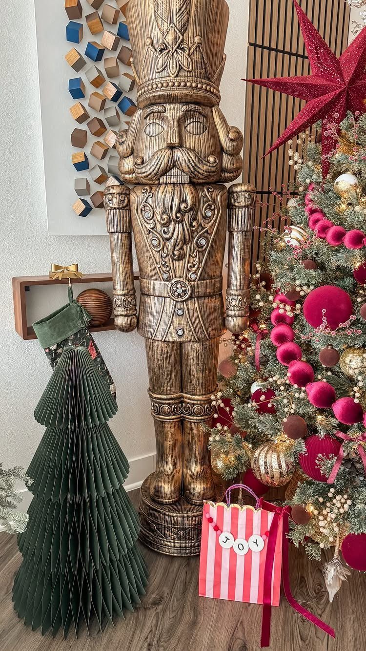 Large wooden nutcracker figure standing next to a decorated Christmas tree and paper tree.