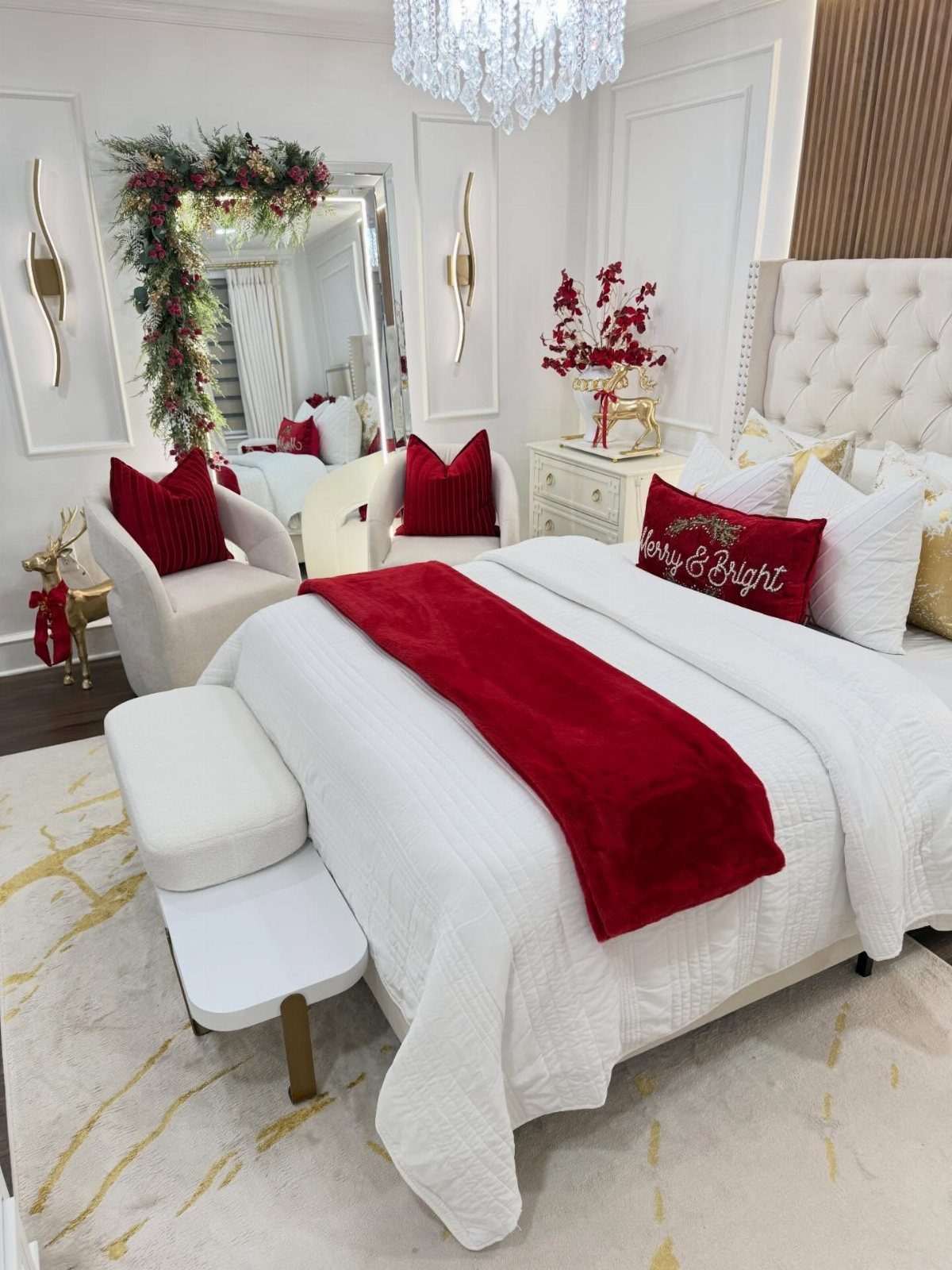 White bedroom with red velvet accents and a festive evergreen garland over a mirror