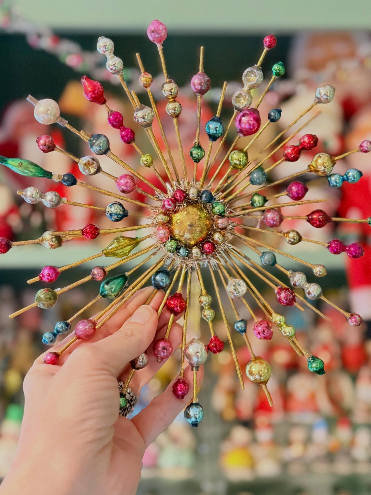 Starburst Christmas ornament with colorful glass beads held by a person's hand.